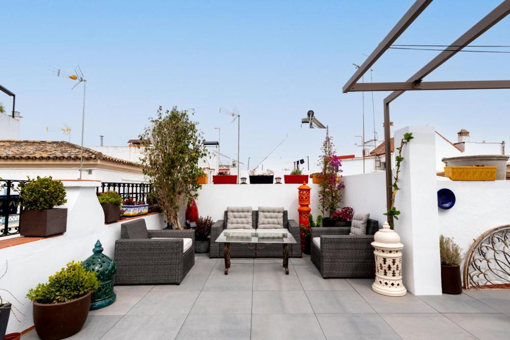 a patio with wicker furniture on a white wall at La Casa (Casa familiar Premium) in Seville