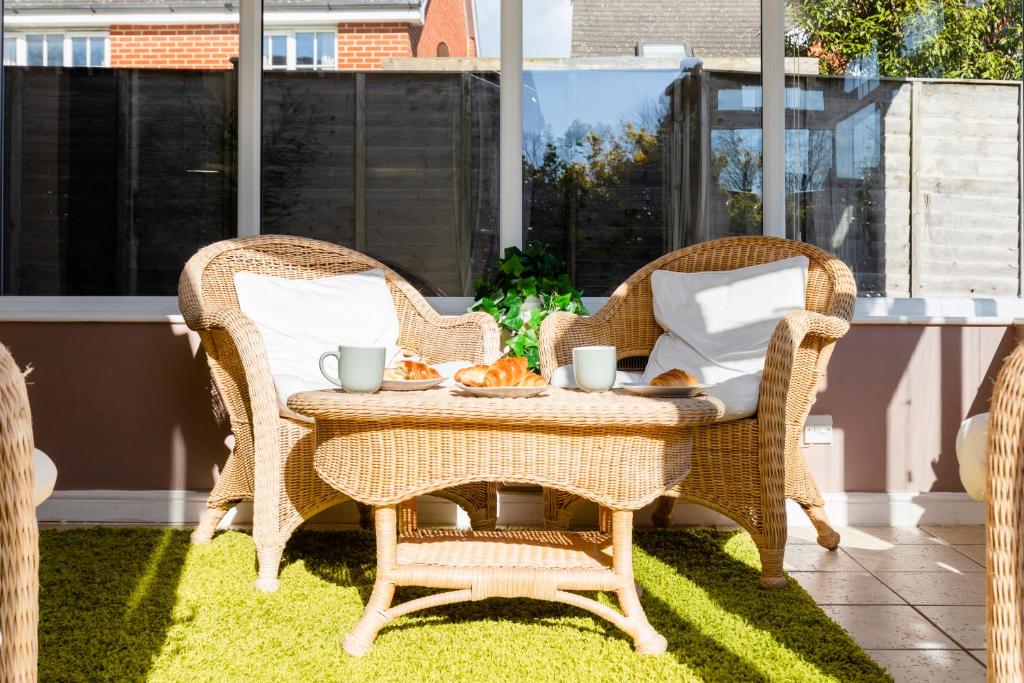 two wicker chairs and a table on a patio at Chichester retreat house with free parking in Chichester