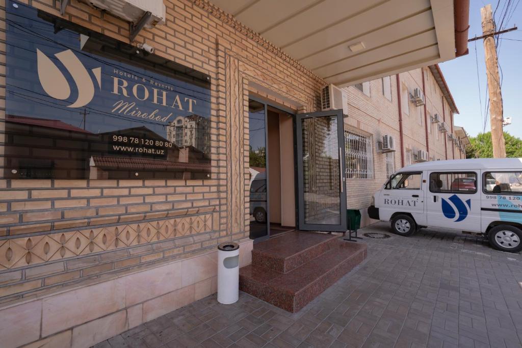 una puerta de entrada de un edificio con una furgoneta aparcada fuera en Rohat Mirobod, en Tashkent