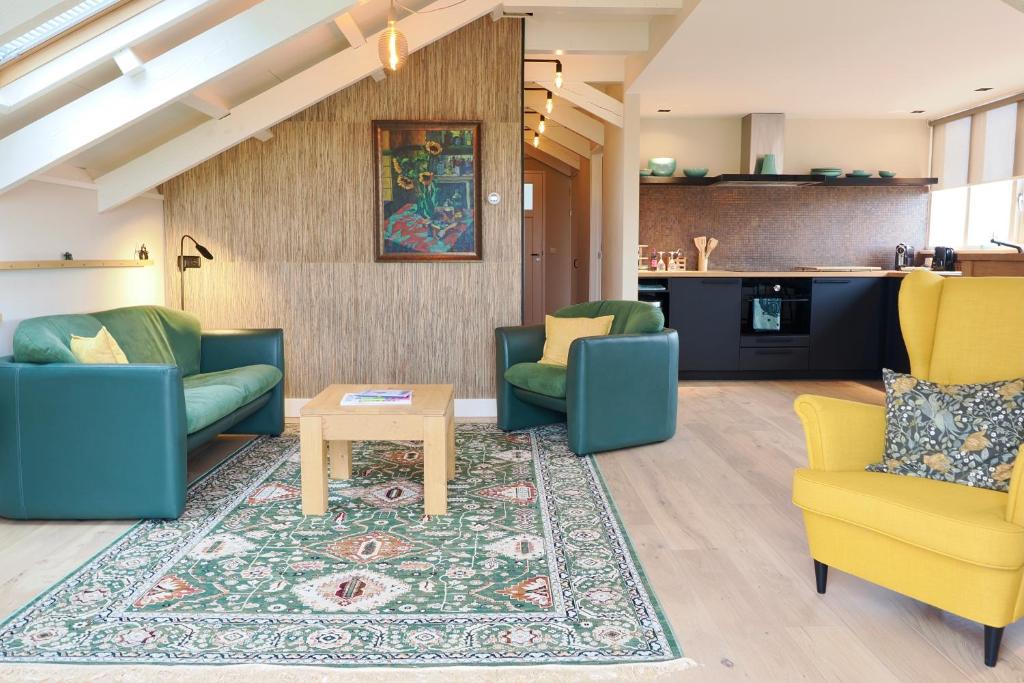 a living room with blue and yellow chairs and a rug at Vakantiehuis Noflik Nijemirdum in Nijemirdum