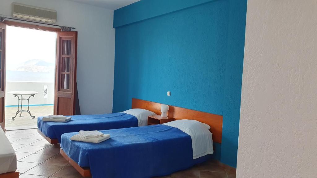 Duas camas num quarto com uma parede azul em Blue Sand em Calímnos