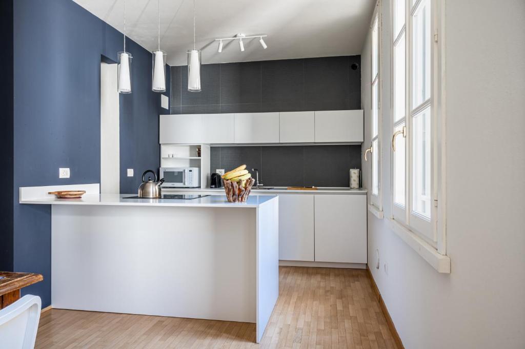 a kitchen with white cabinets and blue walls at Officina7 Large in Parma