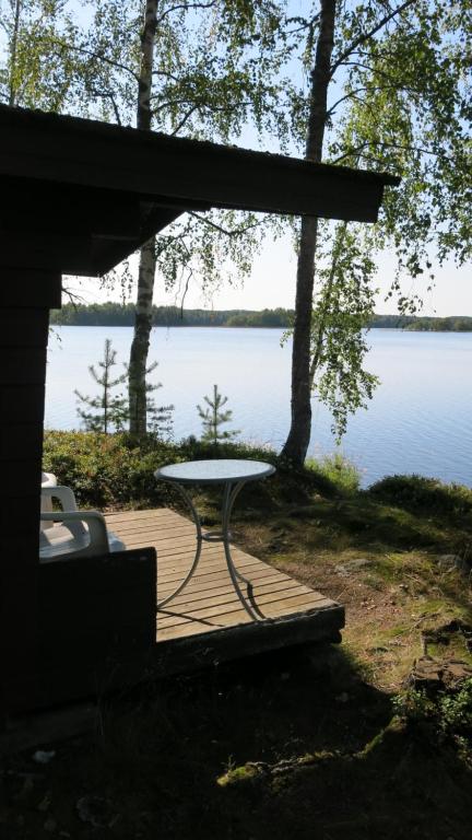 a picnic table sitting on a deck next to a lake at Marjoniemi Camping in Hiidenniemi