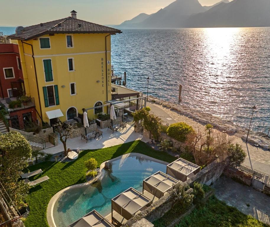 a building with a swimming pool next to a body of water at Lake Front Hotel Brenzone in Brenzone sul Garda