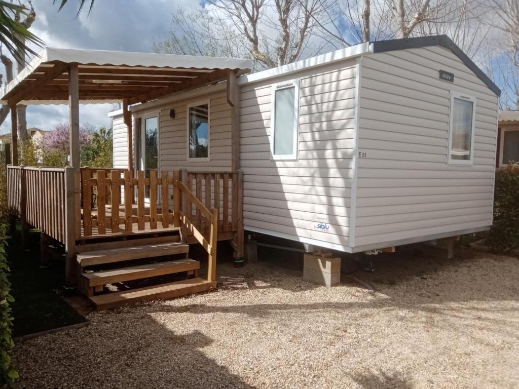 ein weißes winziges Haus mit einer Veranda und einer Rampe in der Unterkunft MOBIL HOME DU ROUTIER in Valras-Plage