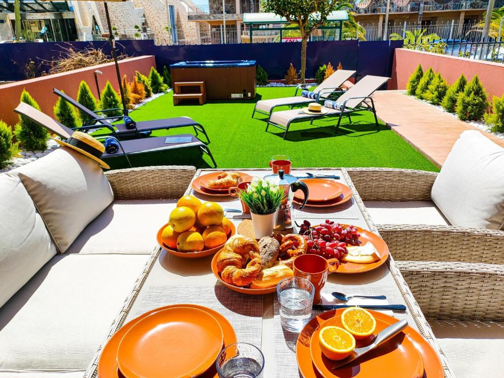 a table with orange plates of food on a patio at Lemon Terraced House in Playa del Ingles