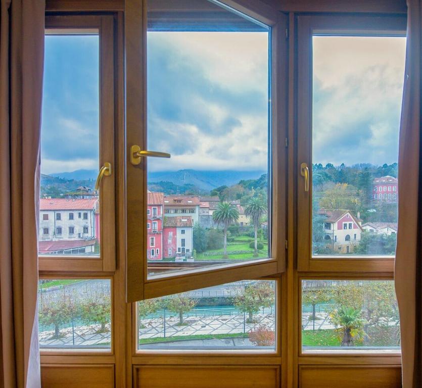 a window with a view of a city through it at Apartamentos Camparina in Llanes