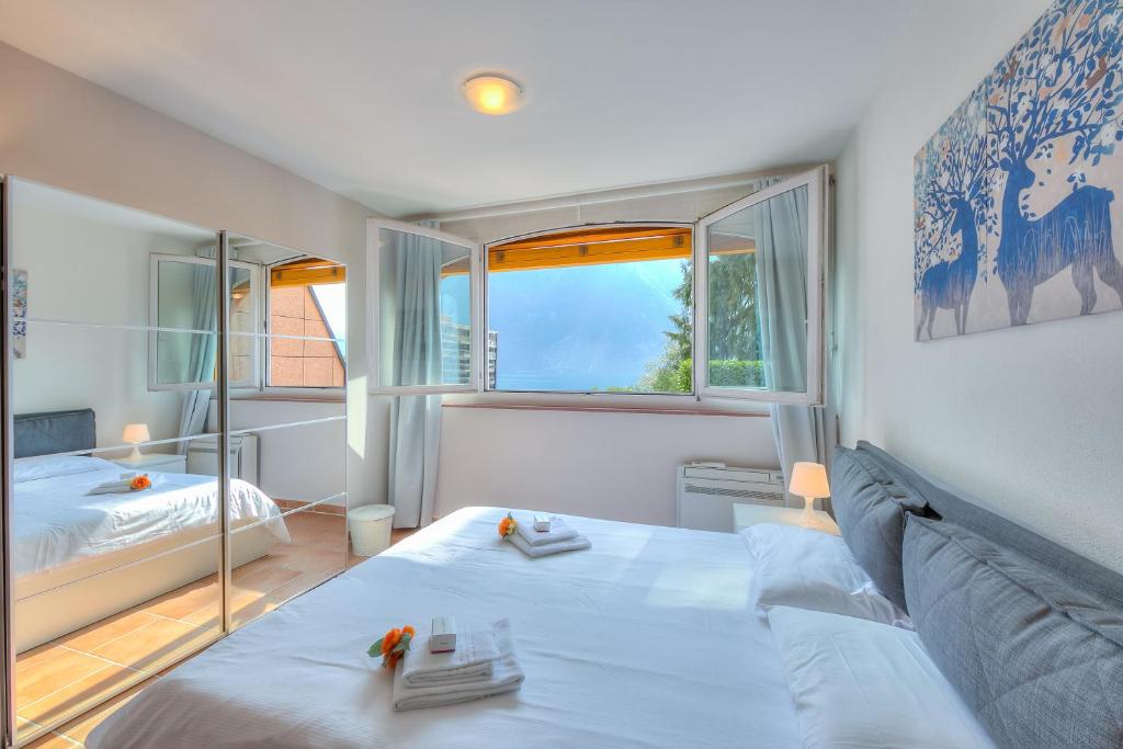 a bedroom with a bed and a large window at Apartments Gelsomino, Orchidea and Magnolia in Castagnola