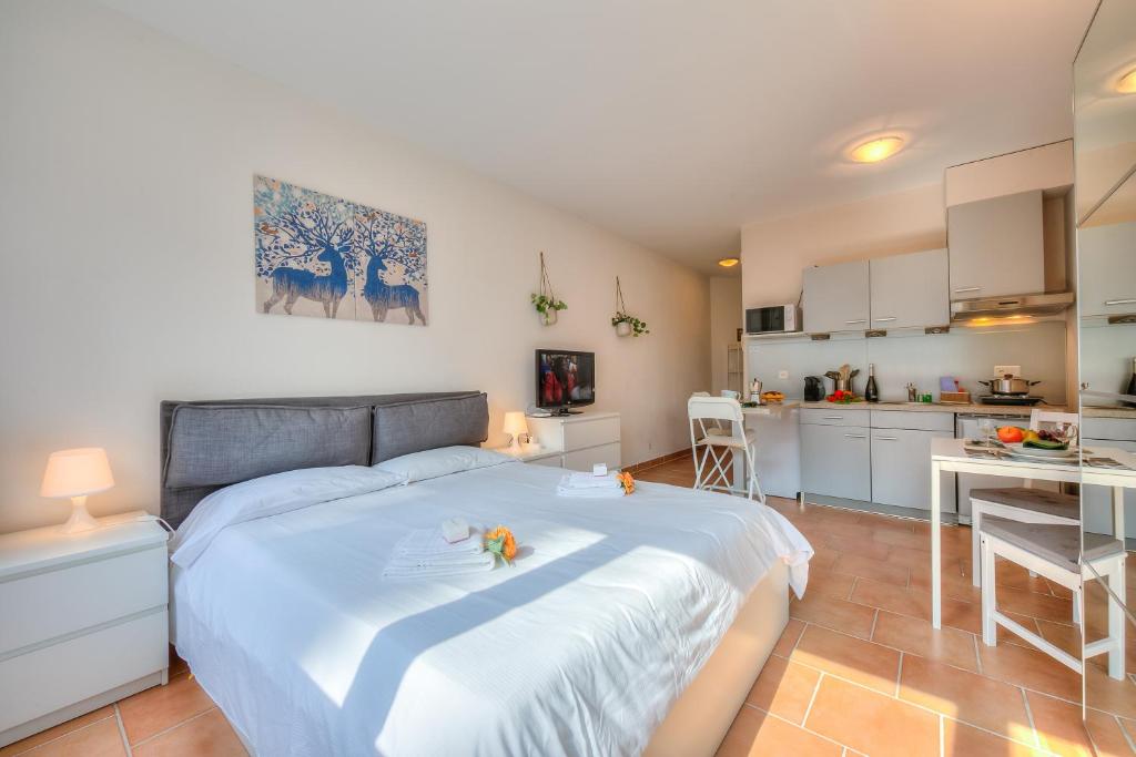 a bedroom with a large white bed and a kitchen at Apartments Gelsomino, Orchidea and Magnolia in Castagnola