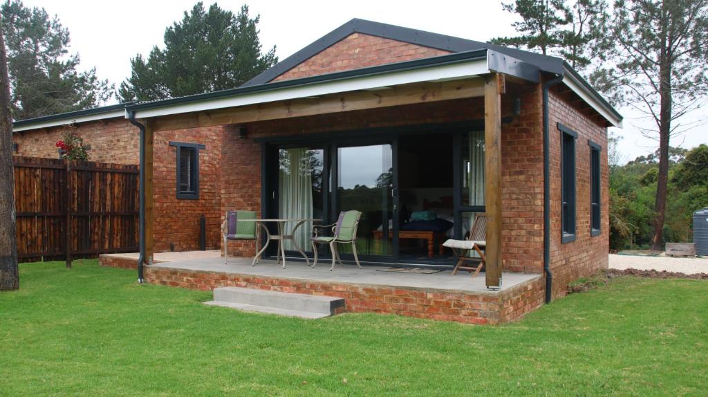 a brick house with a patio with a table and chairs at Beessential Farm in The Crags