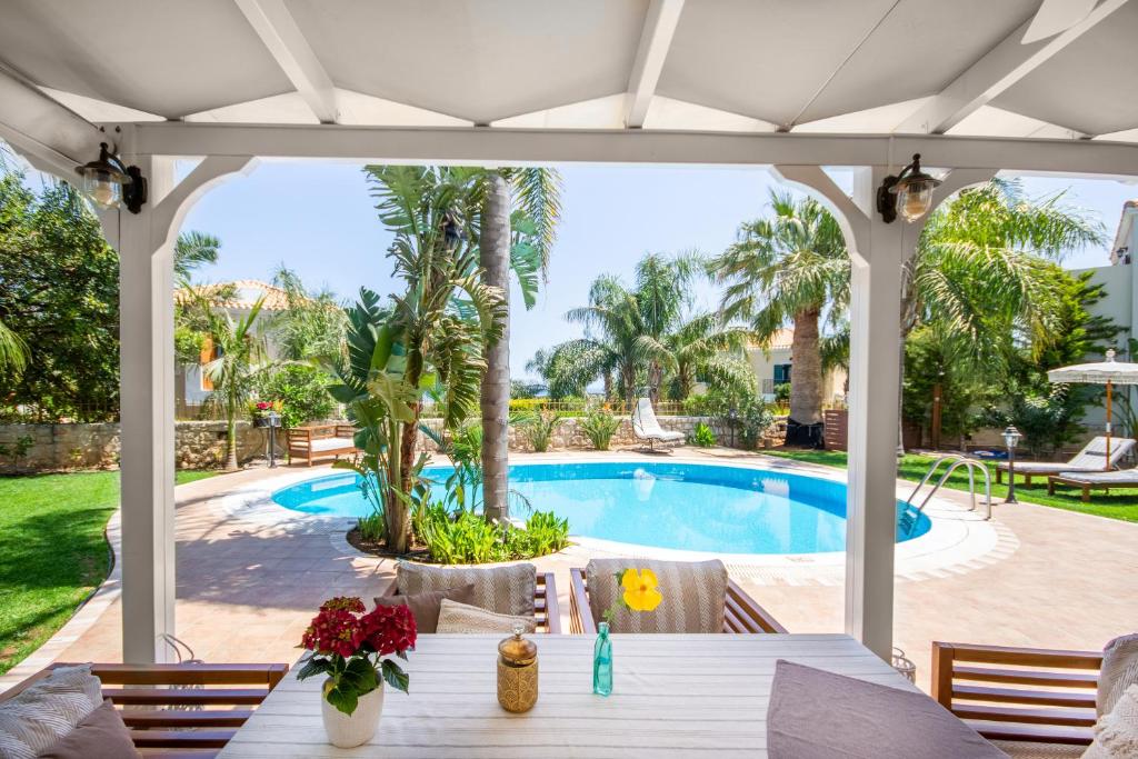un patio con una mesa y una piscina en Pandora Villas en Hersonissos