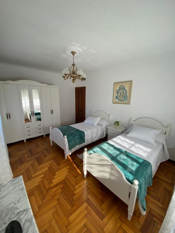 two beds in a room with wood floors and a chandelier at Casa Teresa in Redondela