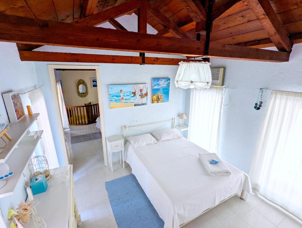 a bedroom with a white bed and some windows at Ύδρα ivY in Hydra
