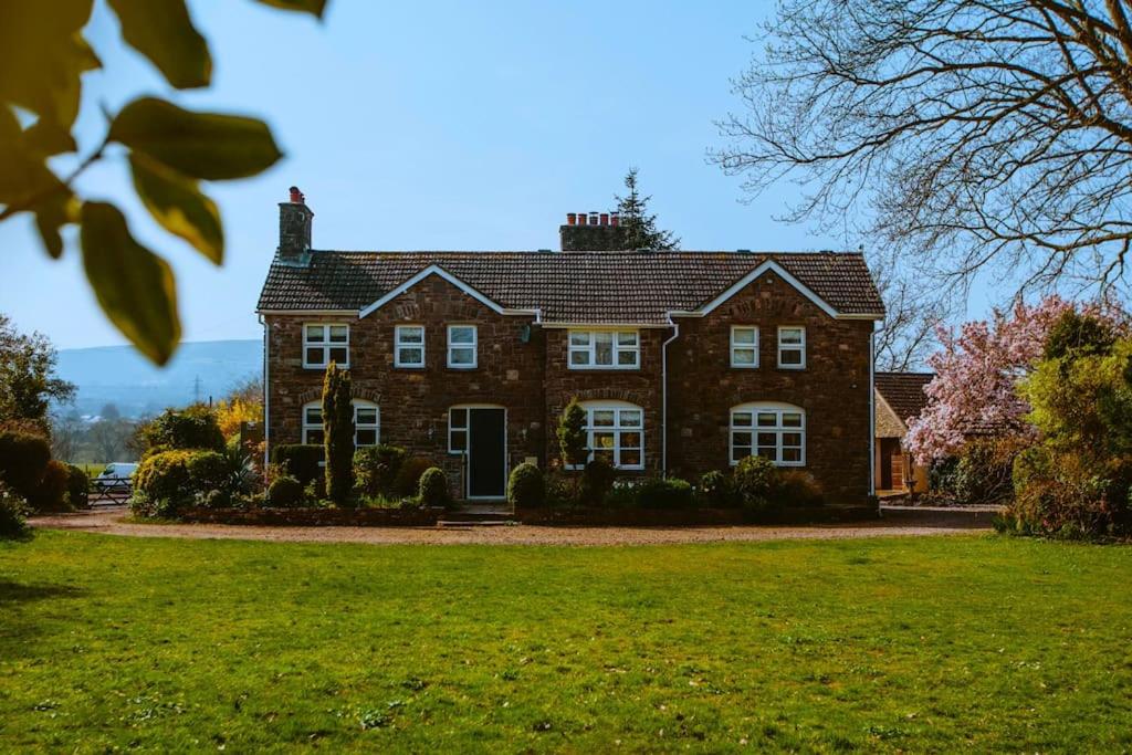 a large brick house with a green lawn at Beautiful 5 bedroom house with hot tub & fire pit in Abergavenny