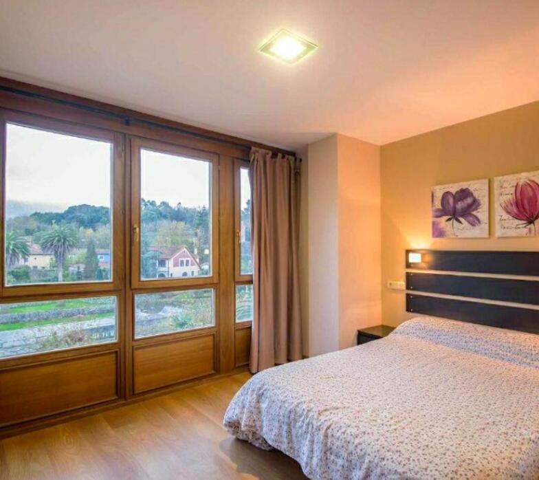 une chambre avec un lit et une grande fenêtre dans l'établissement Apartamentos Camparina, à Llanes