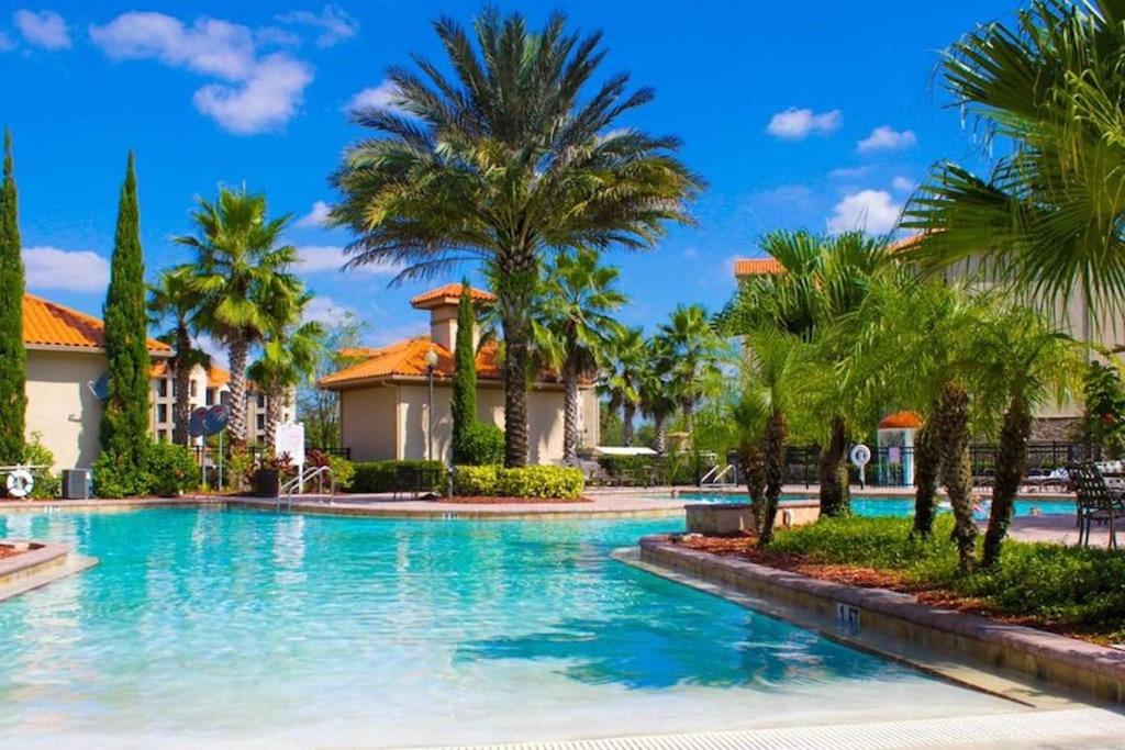a swimming pool in a resort with palm trees at Disney Memories at Tuscana Resort in Kissimmee