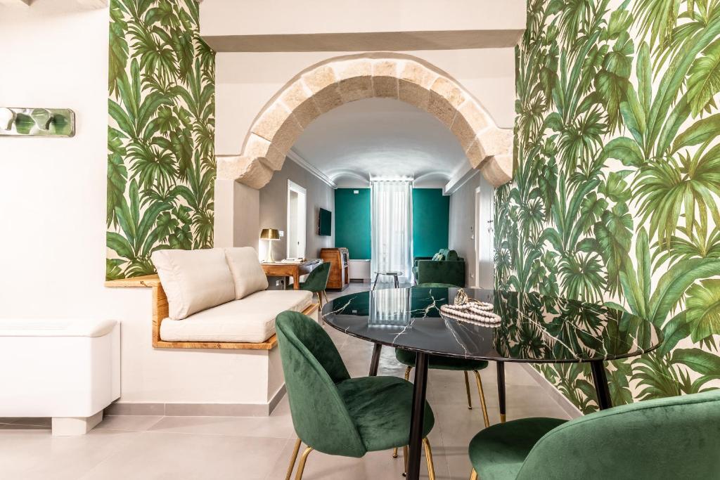 a living room with a table and green chairs at Ortigia's Queen in Siracusa