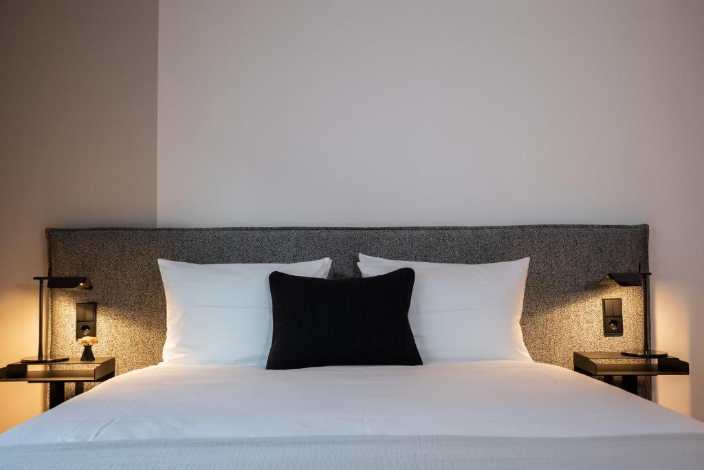 a large bed with white sheets and black pillows at HOtello Lehel in Munich