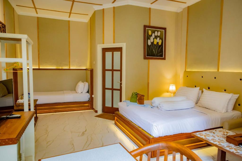 a bedroom with two beds and a table and a desk at Family Hotel Gradia 1 in Batu