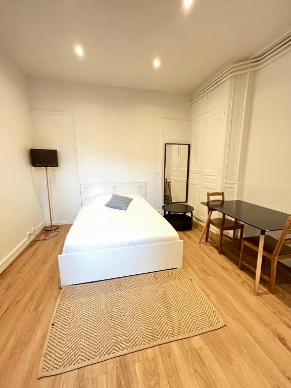 une chambre avec un lit blanc et une table dans l'établissement Le Jardinet, face à la Cathédrale, baignoire - RDC, à Reims