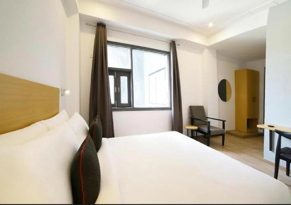 a bedroom with a white bed and a window at Hotel Mavens Orange Gurgaon in Gurgaon