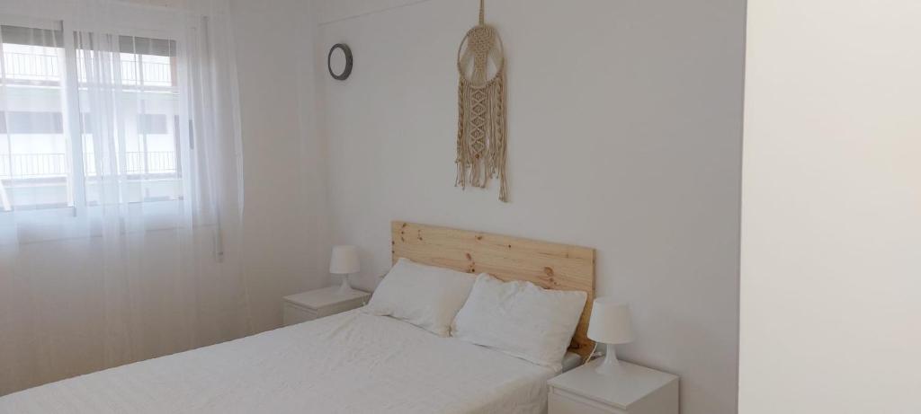 a white bedroom with a bed and a window at Apartamento Ferrandis Benicasim in Benicàssim