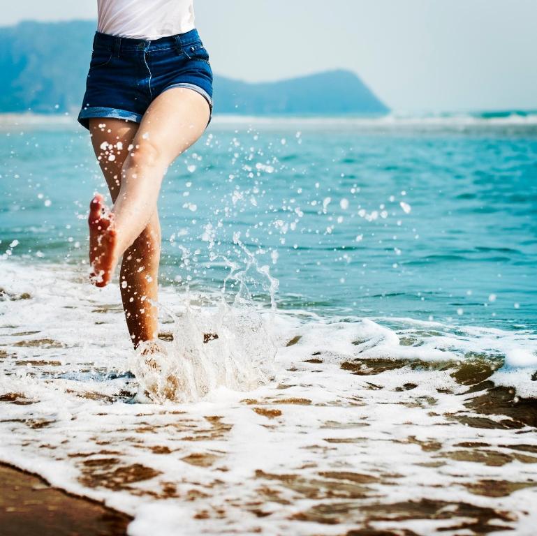 Una mujer corriendo al agua en la playa en Hostal Moscatel, en Málaga