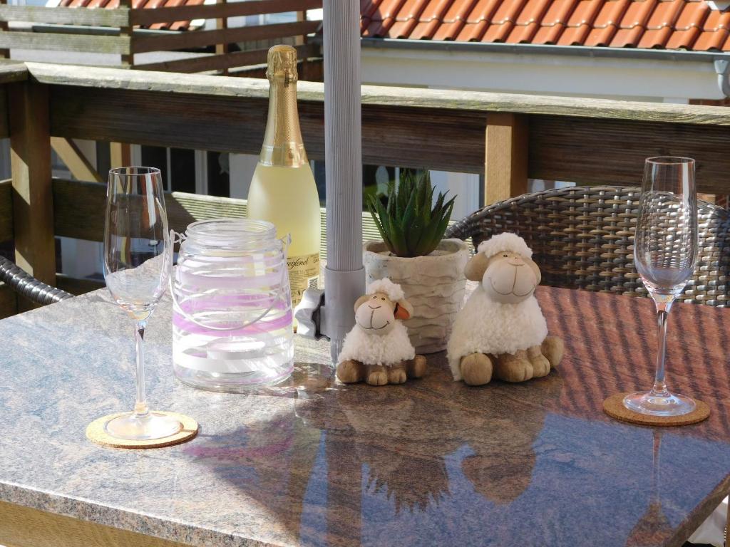 two stuffed sheep sitting on a table with wine glasses at !!!NEU!!! Ferienwohnung am Deich in Dornumersiel