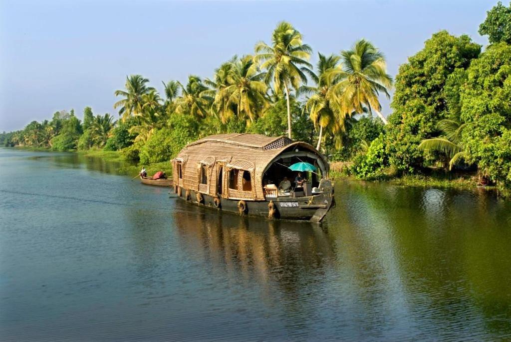 a house boat on a river with palm trees at Kalappura Houseboats & Tours in Alleppey