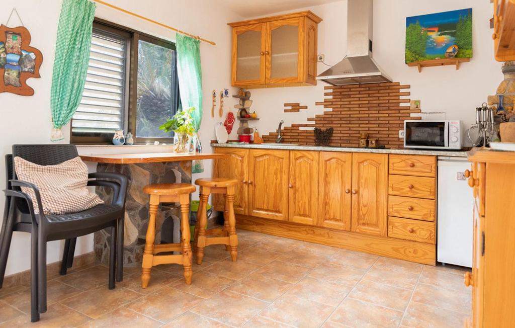una cocina con armarios de madera, mesa y sillas en Casa GRENADO, en Vallehermoso