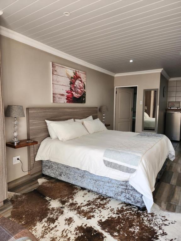 ein Schlafzimmer mit einem großen Bett und einem Gemälde an der Wand in der Unterkunft Schnehage Self Catering in Bloemfontein