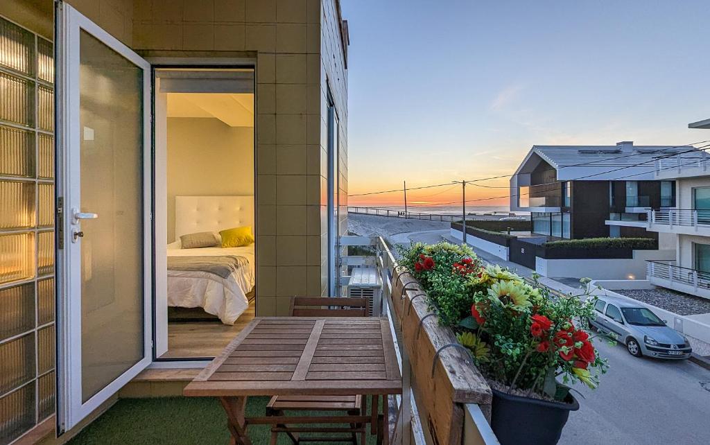 uma varanda com uma cama, uma mesa e flores em Costa Nova Ocean View em Gafanha da Encarnação