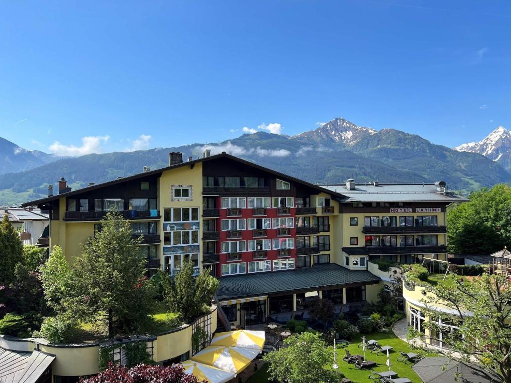 a large building with mountains in the background at Hotel Latini in Zell am See