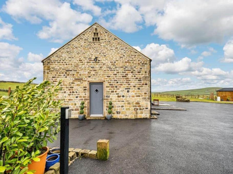 a brick barn with a door in a parking lot at Rita's Roost, Lancs, tranquil with amazing views in Burnley