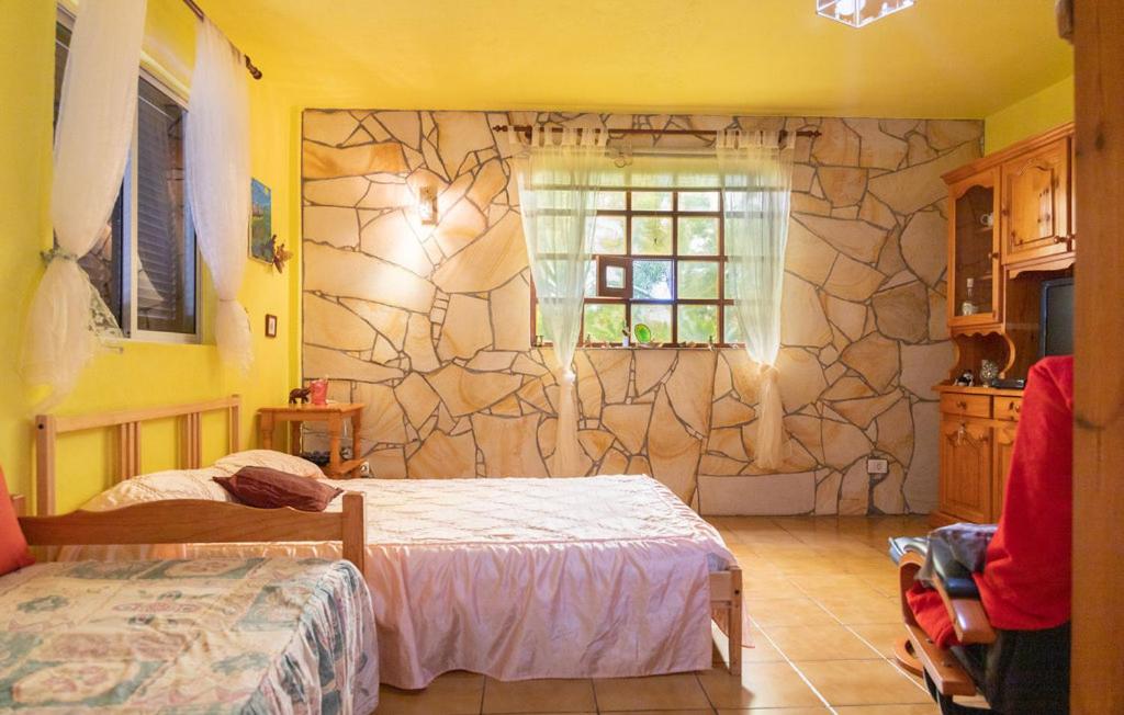 1 dormitorio con 2 camas y pared de piedra en Casa Majores, en Lo del Gato
