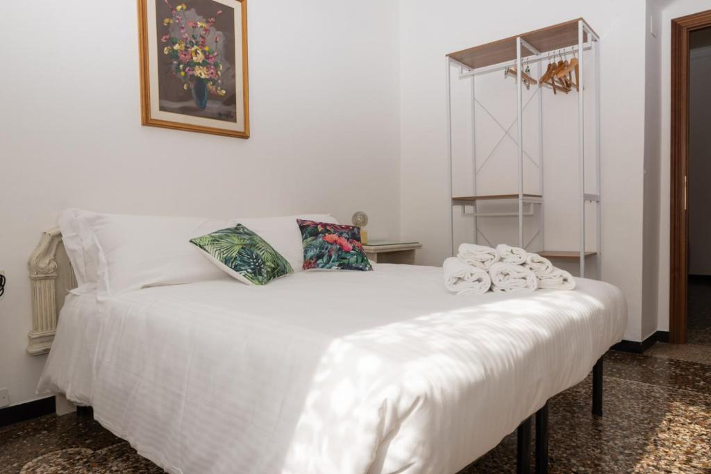 ein weißes Bett mit Handtüchern auf dem Zimmer in der Unterkunft Living Sestri Airport in Genua