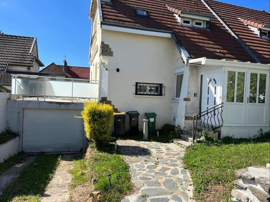una casa blanca con una puerta y un garaje en Jolie maison de ville avec terrasse et jardin, en Warcq