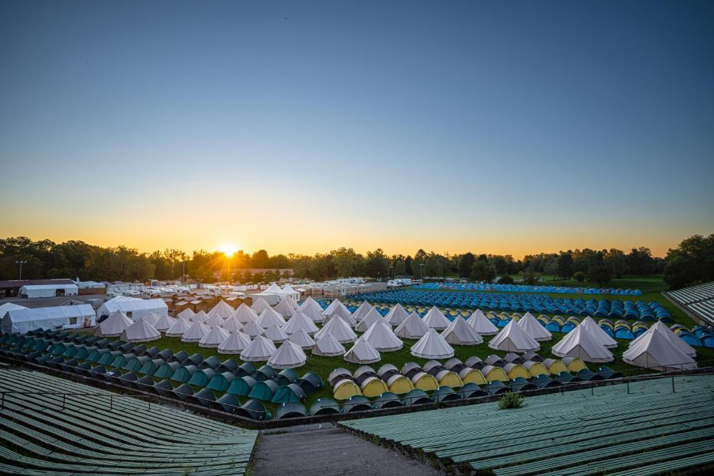 a group of white tents in a field with the sunset at Wies'n Camp in Munich