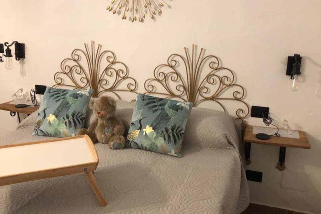 um urso de peluche sentado numa cama com duas almofadas em Camera Privata Orchidea em Castellero