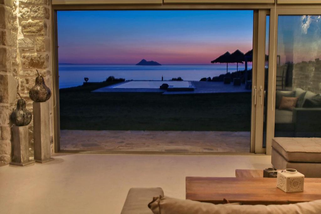 a living room with a view of the ocean at Beachfront villa Komos with heated pool in Kalamaki