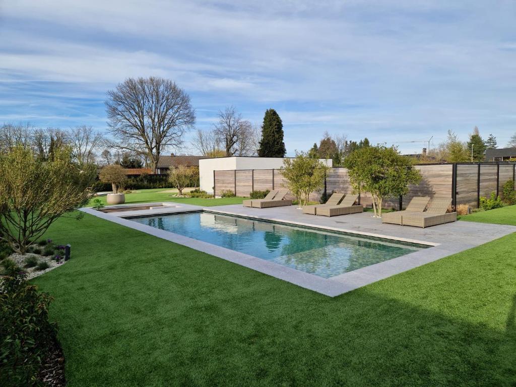 una piscina en un patio con césped verde en Guesthouse Andor, en Balen