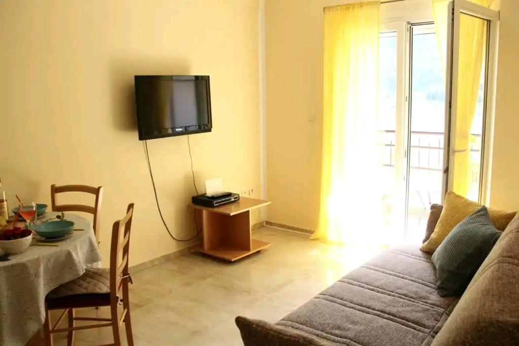 sala de estar con sofá, mesa y TV en Aurora Apartments en Igalo