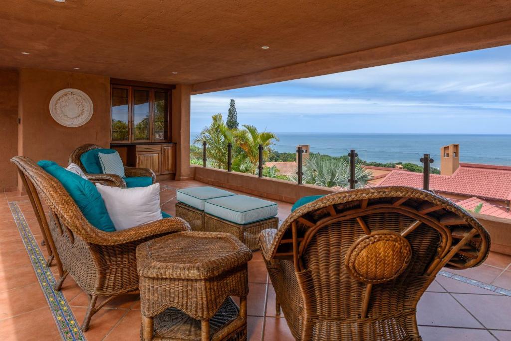 a patio with chairs and a table and a view of the ocean at San Lameer Villa 13934- 4 Bedroom Deluxe - 8 pax- San Lameer Rental Agency in Southbroom