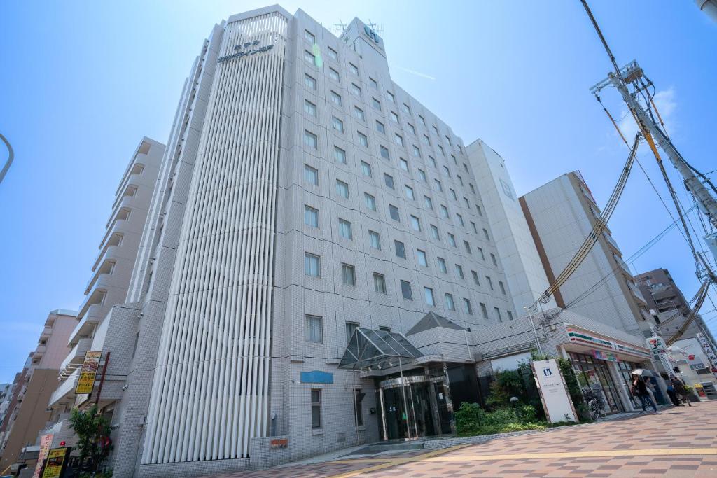 a tall white building on a city street at Hotel Casabella Inn Kobe in Kobe