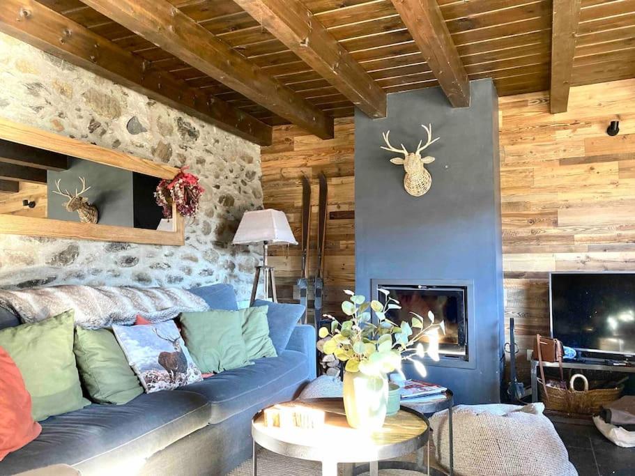 a living room with a blue couch and a stone wall at Xalet Montana in Ur