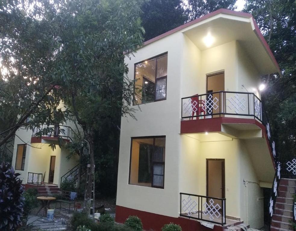 Una casa blanca con balcones en un lateral. en Nalgarh Retreat - JUNGLE RESORT by StayApart, en Uttar Simlabari