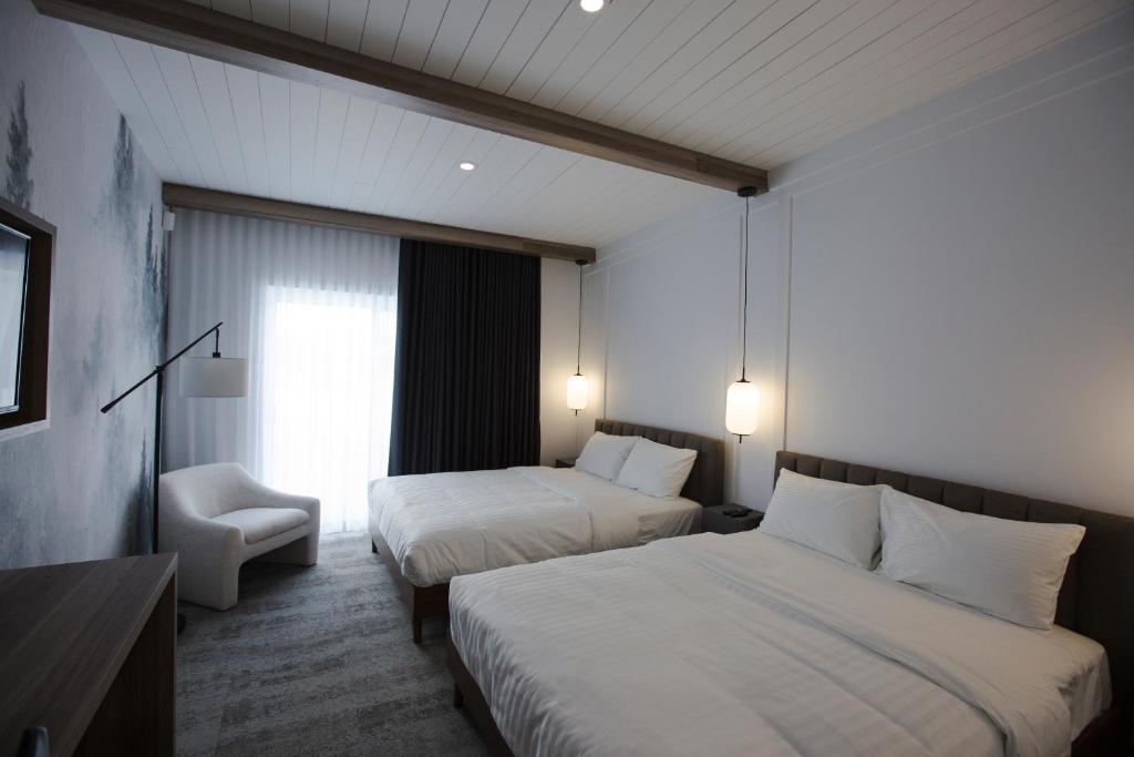 um quarto de hotel com duas camas e uma cadeira em Hotelia em Saint-Ambroise