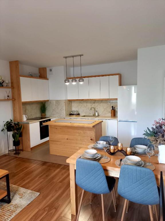 cocina con mesa de madera y sillas azules en Apartament Green Park 2 en Starogard Gdański