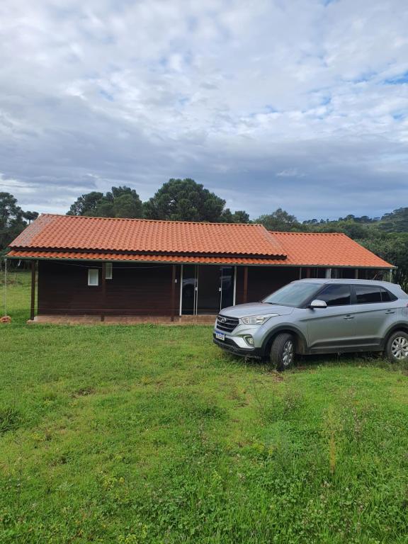 un coche aparcado en un campo frente a una casa en Casa p fim de semana en Urupema
