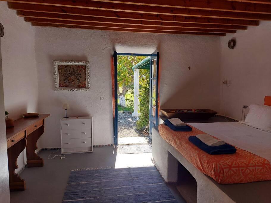 a bedroom with a bed and a desk and a window at Arancio independent room in Ecovilla on the beach in Apolakkiá